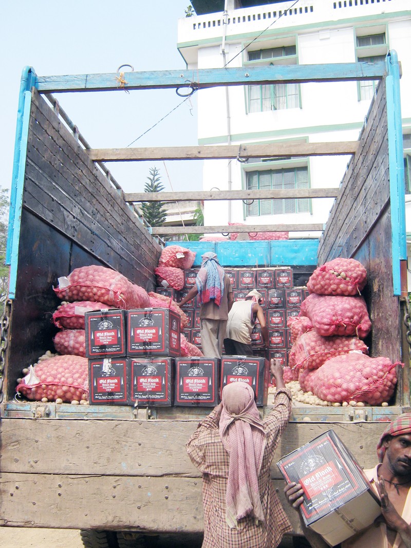 CORE ISSUE: Seized illicit liquor, hidden under sacks of onion, being unloaded at a police station in Dimapur. (File photo)